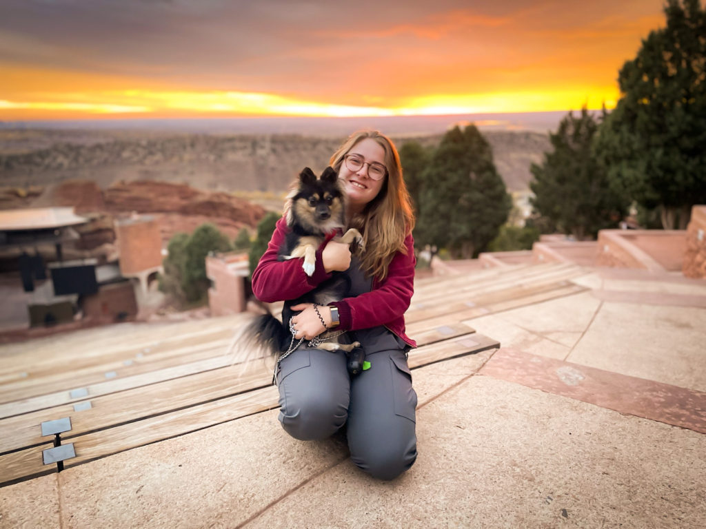 woman holding dog in front of sunrise